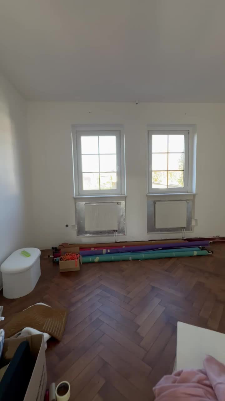 Der helle Studioraum mit zwei hohen Fenstern und Fischgrätparkett, aufgenommen im Studiovideo.
